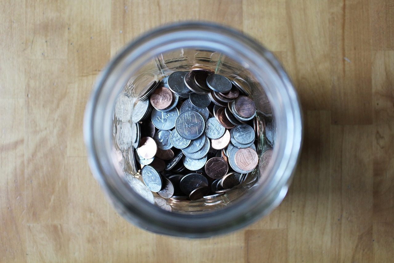A glass jar filling up with coins
