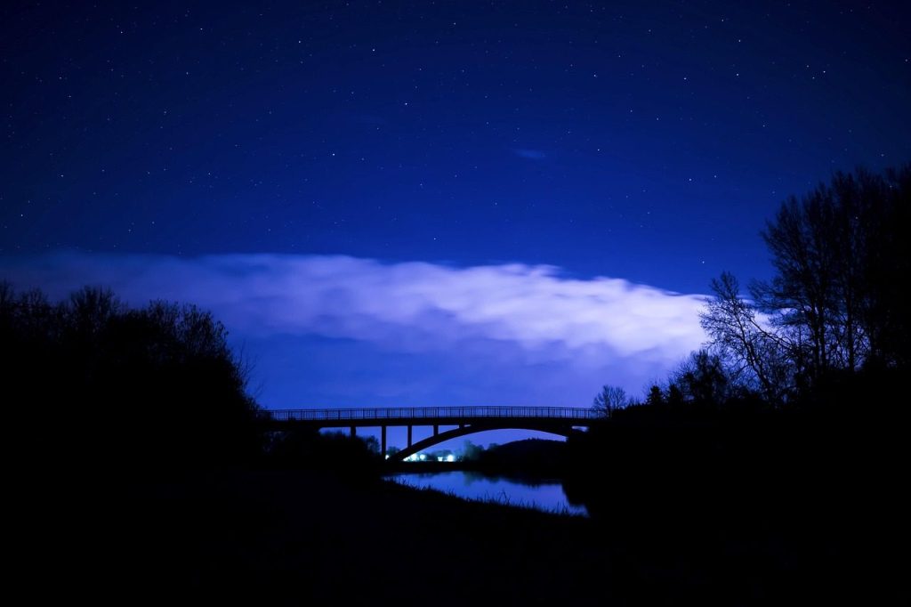 A bridge in silhouette under a deep blue night sky