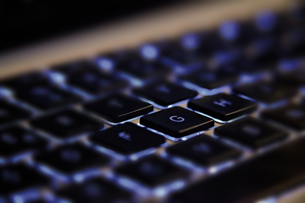 Backlit keyboard keys in close-up, blue under-glow