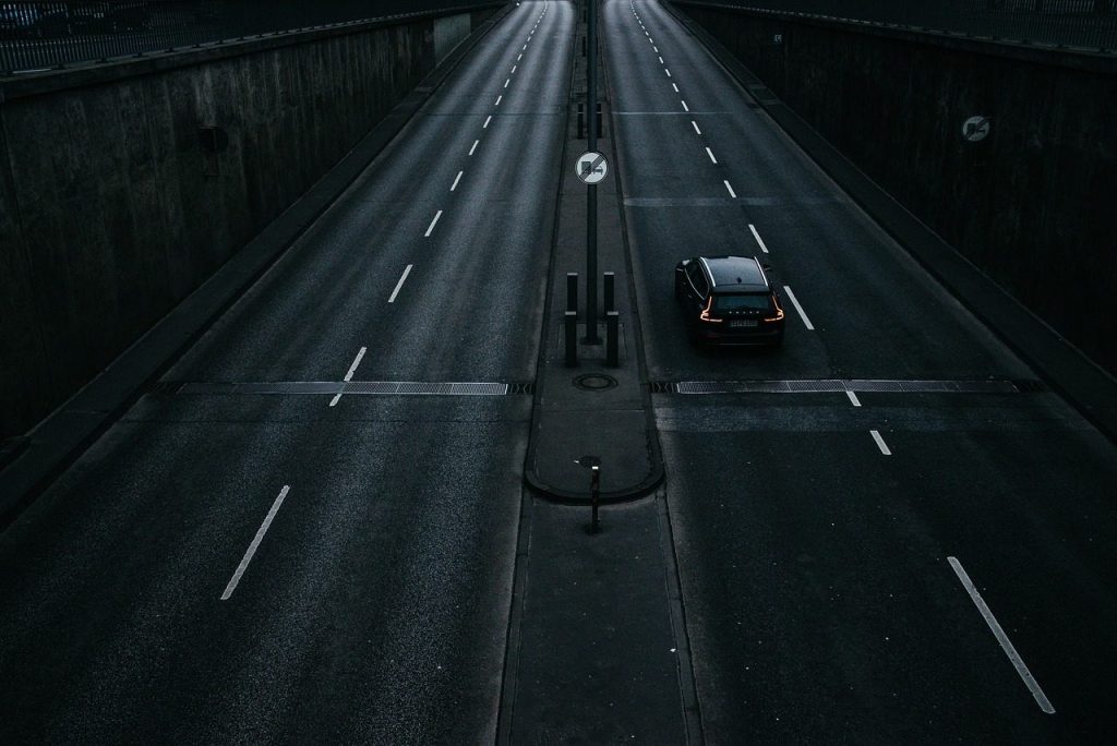 A single car on an empty multi-lane road at night