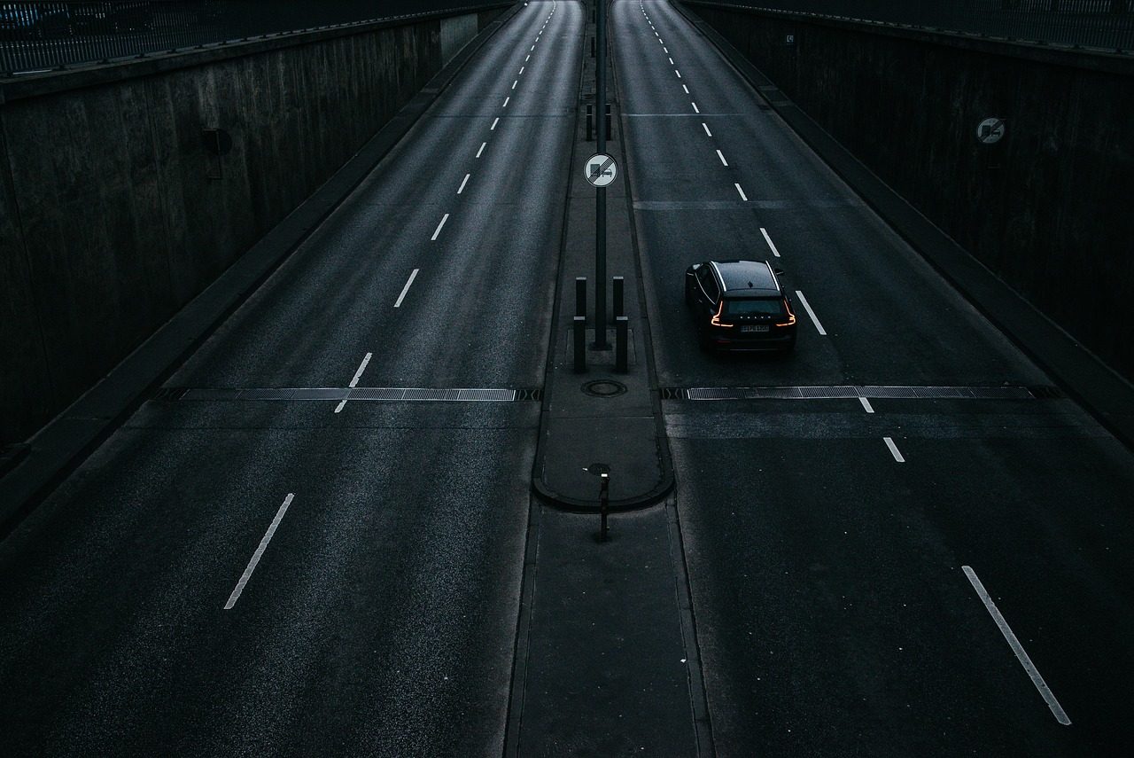 A single car on an empty multi-lane road at night