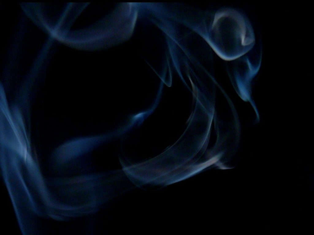 Pale blue smoke curling across a black background