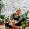 A young woman engaged in indoor gardening, planting various herbs and plants in terracotta pots
