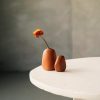Simple ceramic vases with a single orange flower on a table, minimalist style