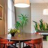 A bright and stylish dining area featuring wooden chairs, plants, and ambient lighting