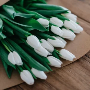 White tulips half wrapped in kraft paper on the workbench.