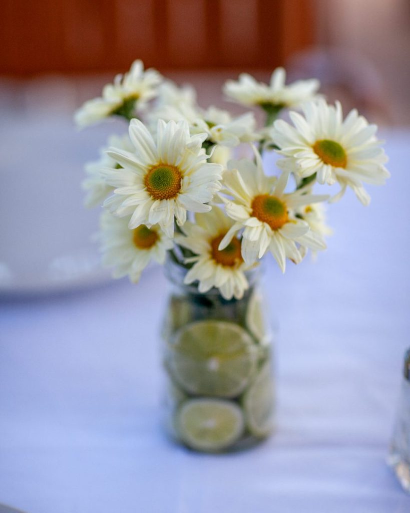 A jar of daisies left on a table after lunch.