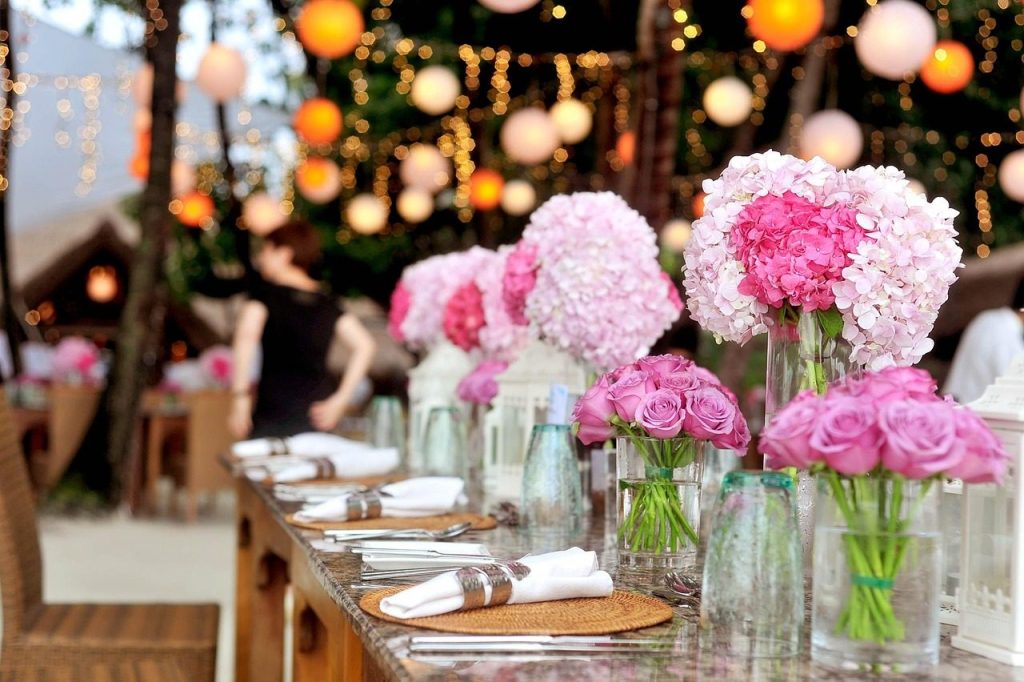 A long table laid for dinner with pink peonies in milk bottles down the middle.